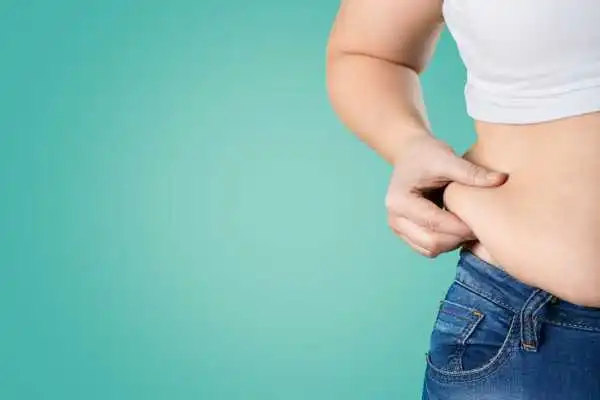 Image of woman pinching her love handles to show weight gain Thames Ditton